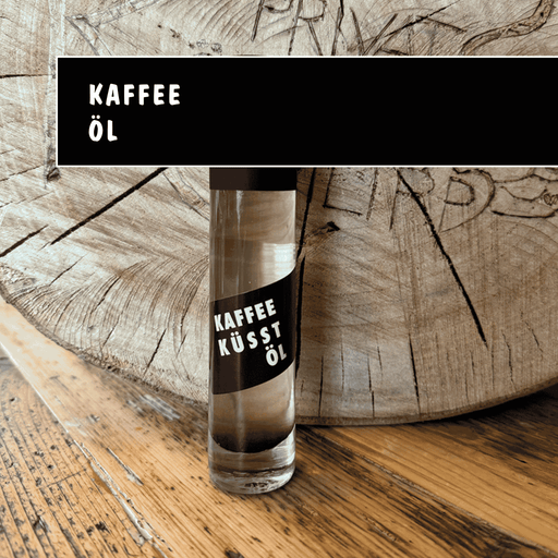Kleine Glasflasche mit Kaffee-Öl vor rustikalem Holz.