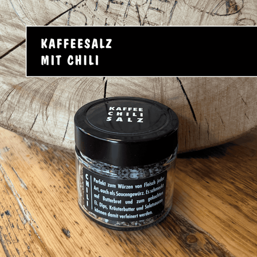 Kleines Glas Kaffee Chili Gewürzsalz mit schwarzem Deckel auf Holzuntergrund, Feinkost aus Kaffeerösterei Nidda.